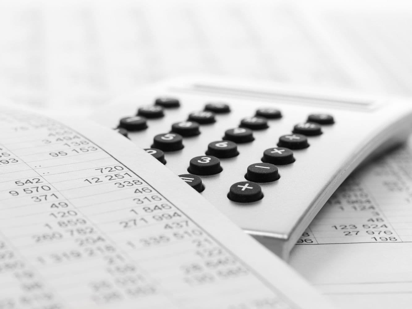 A spreadsheet printout lies on top of a calculator