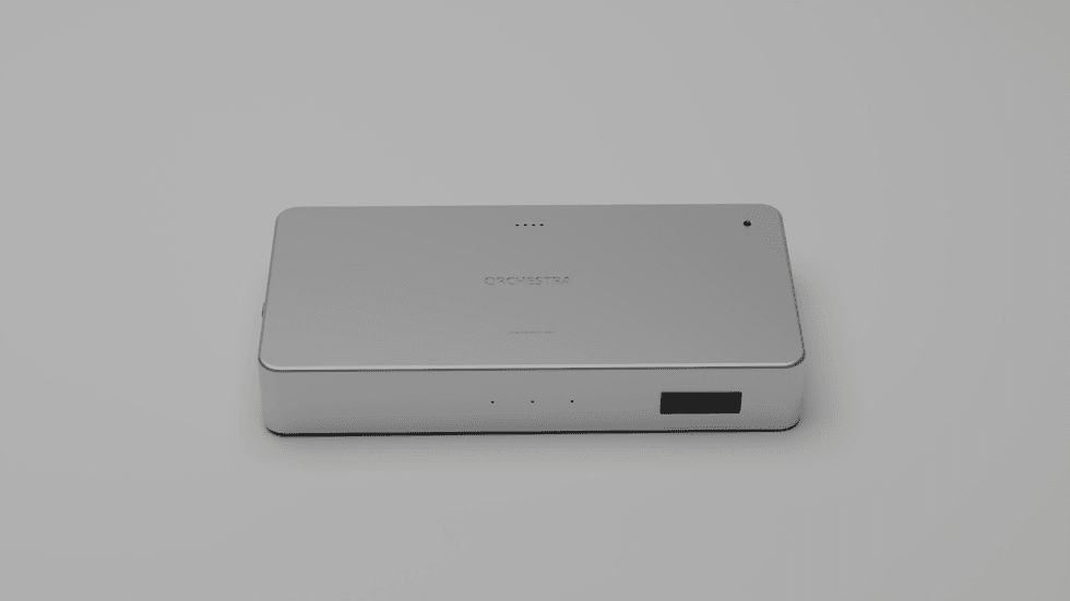 Sleek silver rectangular electronic device labeled \u201cORCHESTRA\u201d on a light gray background.