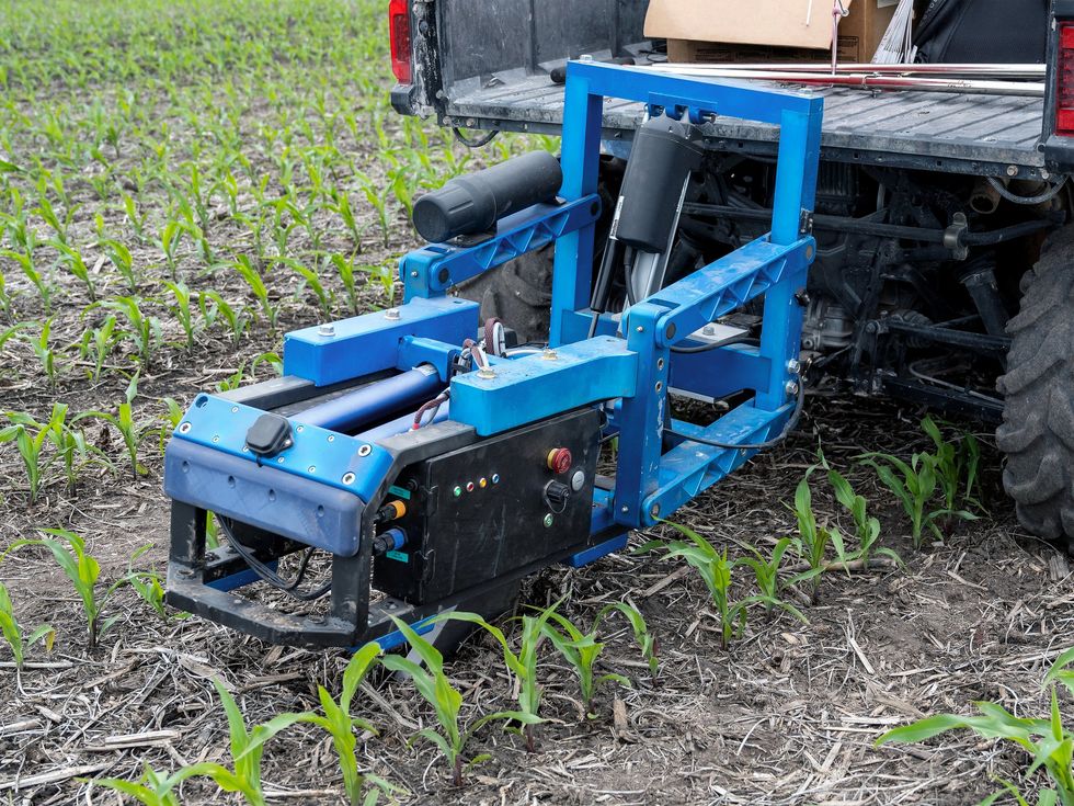 A truck pulling a soil nitrate sensor across a field of crops.