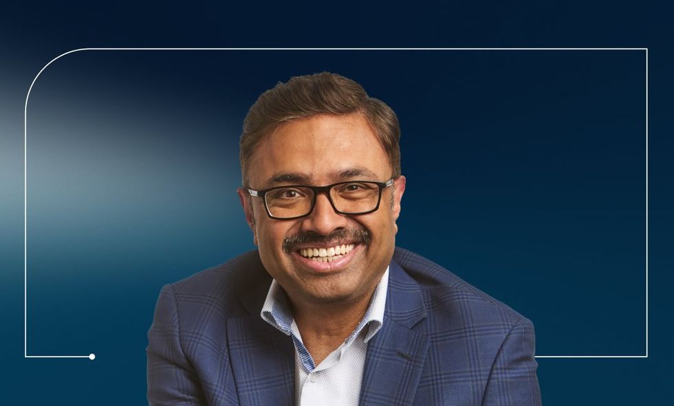 Headshot of a suited man against a blue gradient background.