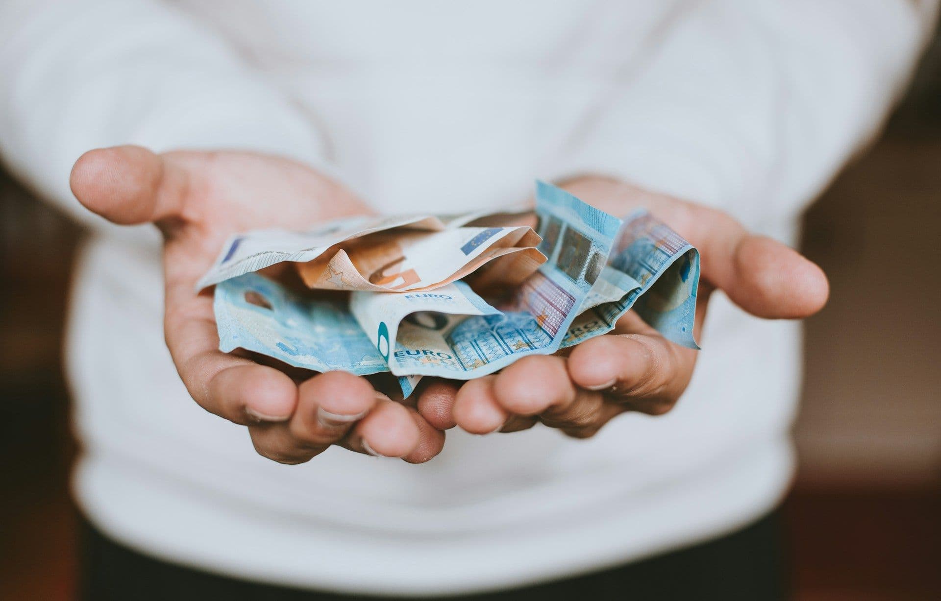 Lending money, bills on a person's hands (Christian Dubovan/Unsplash)
