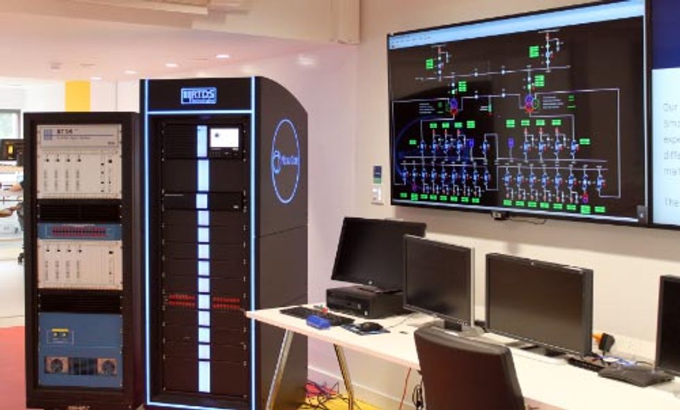 Control room with server racks, workstations, and a large grid monitoring display.