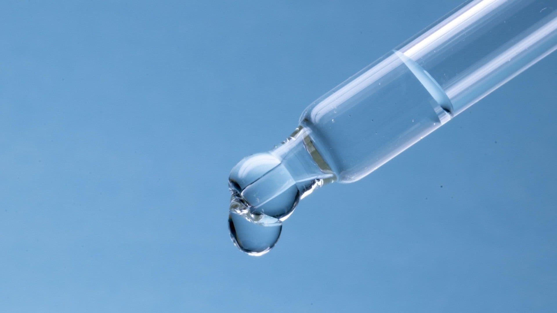 A droplet of water suspended at the end of a pipette.