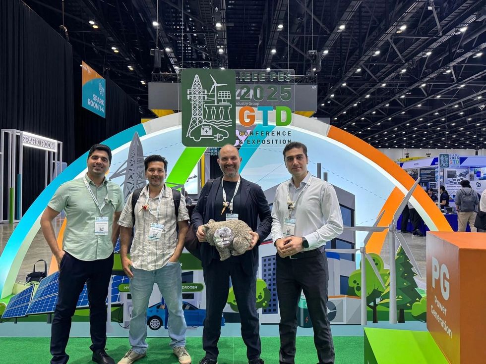 Four men pose at a 2025 GTD conference booth with energy-themed backdrop.