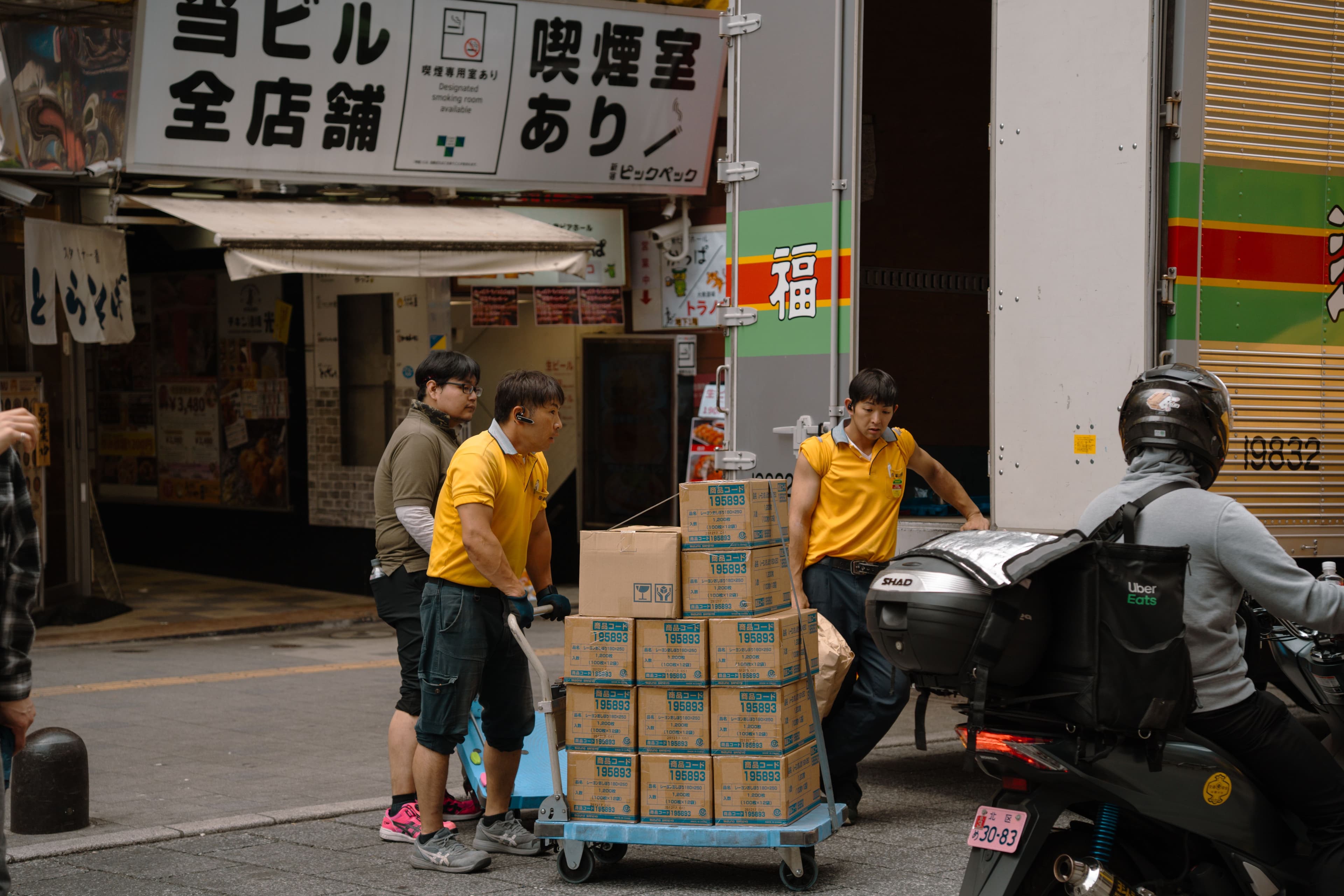 Men in yellow shirts delivering boxes in Tokyo. (Iban Lopez Luna/Pexels)