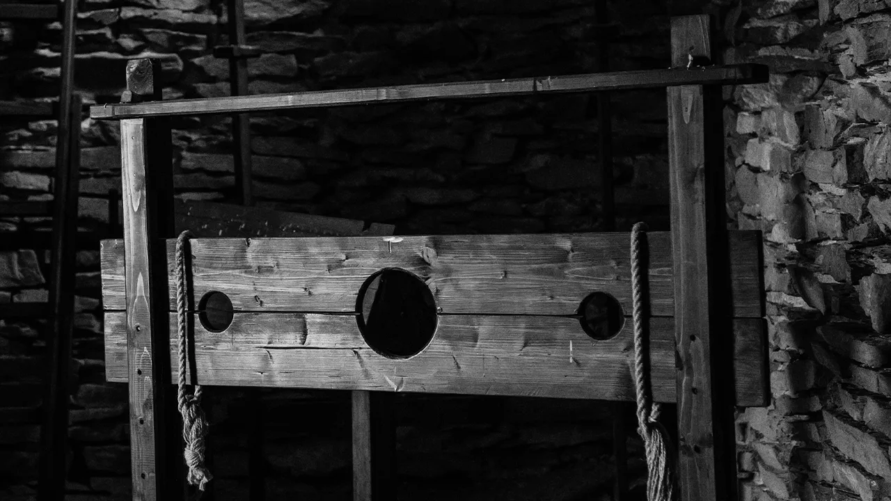 A black and white photograph of a medieval stock in a dungeon