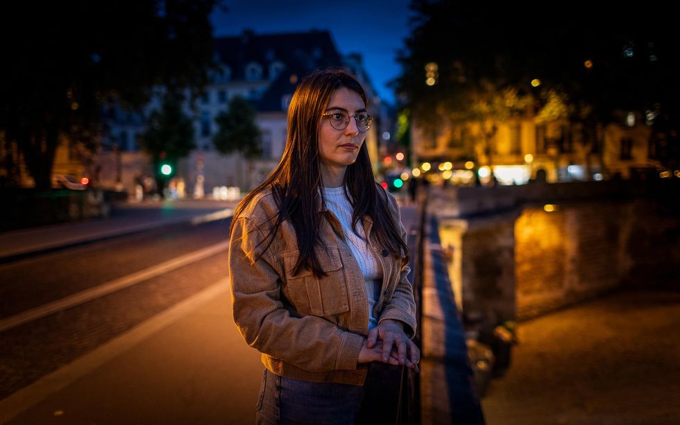 A researcher stands on the Pont de l'Archev\u00each\u00e9 (Archbishop's Bridge) observing the Notre-Dame cathedral at night.