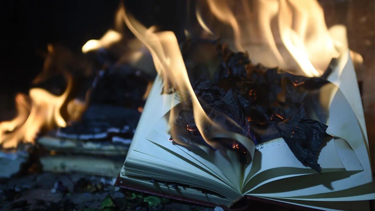 A burning book that has been tossed on the ground