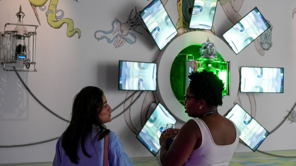 Two people view a circular digital art installation of glowing screens and green light.