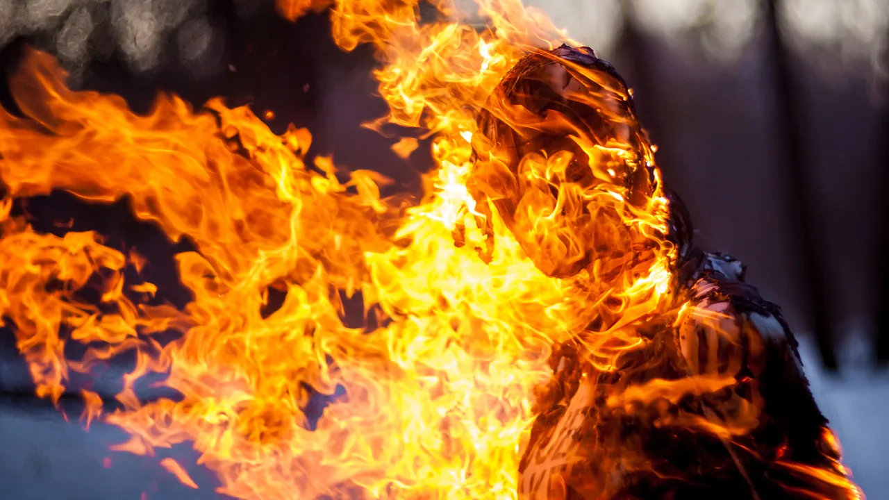 A hooded woman in flames.